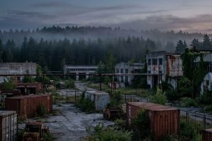 Заброшенный промышленный комплекс в тумане на фоне леса